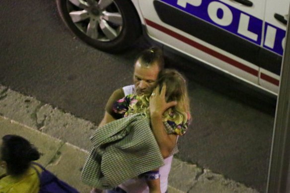 A man holds a child after a truck plowed through Bastille Day revelers.