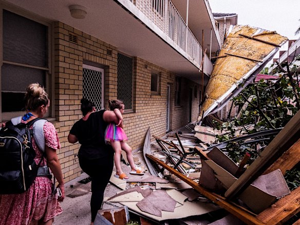 Residents carry children over debris to assess damage in Dee Why, where roofs were ripped off during the “microburst” , a severe storm downdraft often with winds exceeding 100kph.  