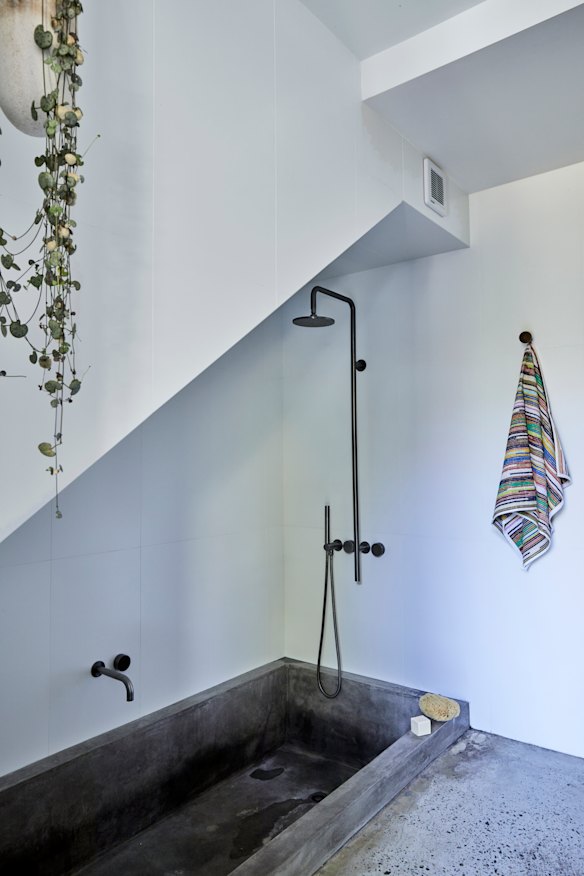 A bathroom tucked under the staircase. “The existing concrete floor was polished and concrete was also used to construct elements such as the bathtub,” says Ben.
