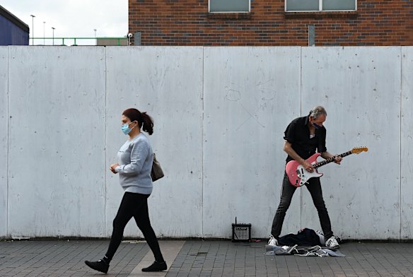 A woman walks past a man busking in Fairfield during the COVID-19 lockdown in an attempt to curb the spread of the virus. Fairfield mayor Frank Carbone said he was hopeful there was a positive way forward for his community after western Sydney mayors met with Premier Gladys Berejiklian this week.