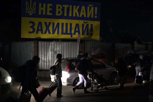 Refugees fleeing the war in Ukraine walk along a road approaching the border with Poland in Shehyni.