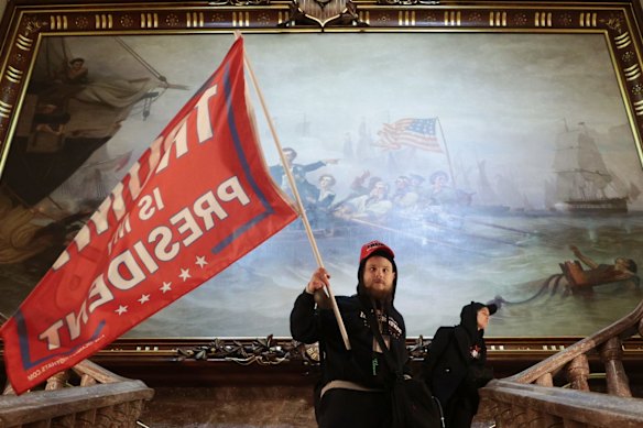 A protester holds a Trump flag inside the US Capitol Building near the Senate Chamber.