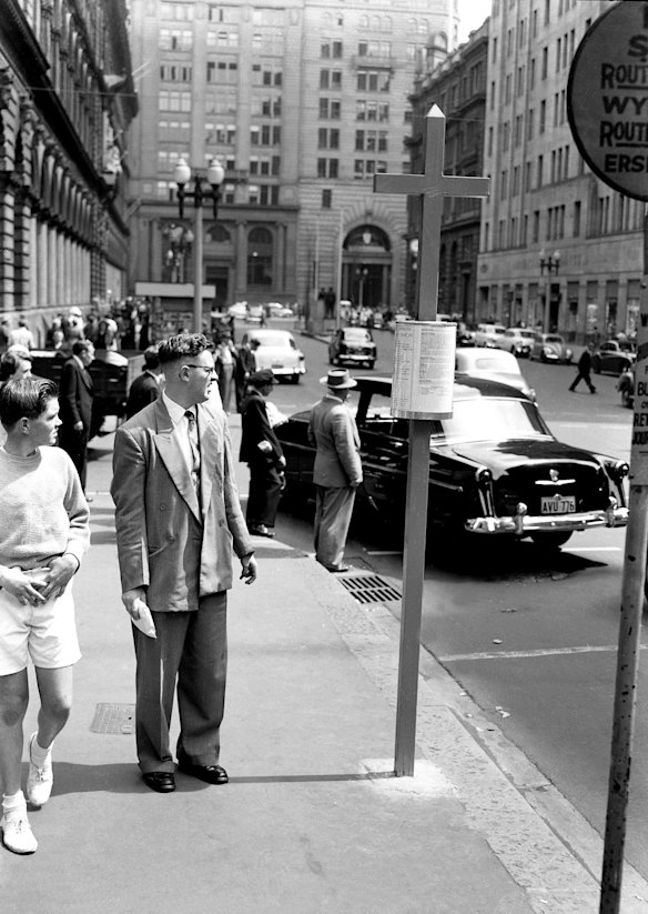 Passengers in Sydney's Martin Place come to grips with the bus timetable during the change-over from trams on 26 September, 1957. 