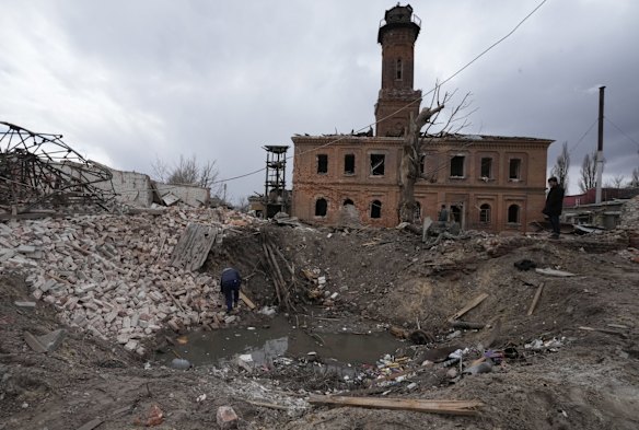 A man inspects a crater caused by a rocket launched by Russian forces during the night in the center of Kharkiv.