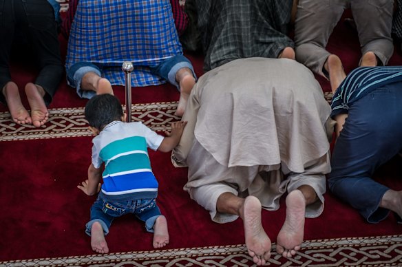 Men and a young boy take part in the early afternoon prayer at Gungahlin Mosque on Saturday.