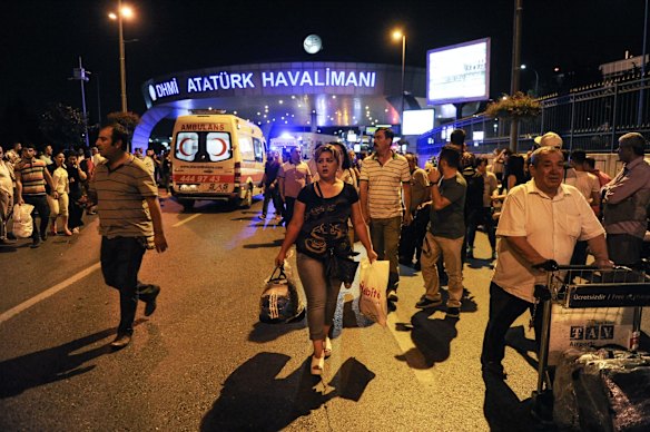 Passengers leave the Turkey's largest airport, Istanbul Ataturk after the suicide bomb attacks as ambulances enter to the site, Turkey.