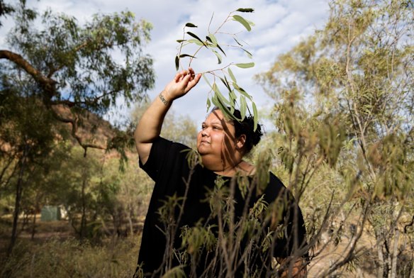 Deanne Wano uses a twig to brush flies away as she gathers arrethe leaves to make into a bush balm for skin conditions. 