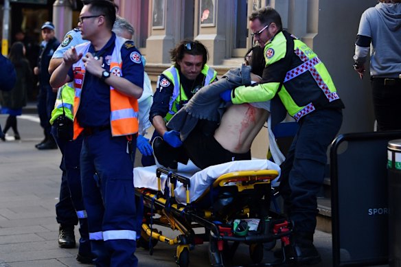 An injured woman is taken by ambulance from Hotel CBD at the corner of King and York streets in Sydney.