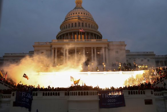 An explosion caused by a police munition is seen while supporters of US President Donald Trump storm the Capitol building. 