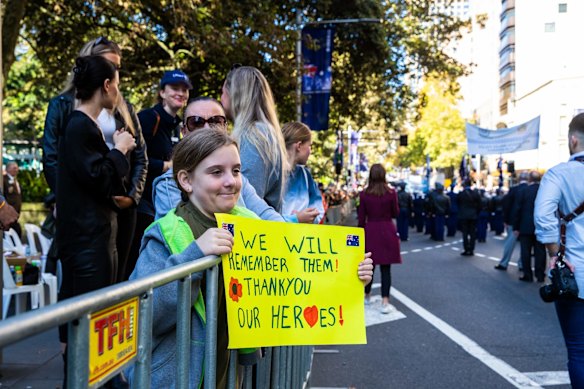 Spectators watch the ANZAC Day march down Elizabeth St, Sydney.