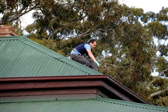 A police officer atop an Elphinstone house, raided in 2008 in connection with the disappearance of Tony Mokbel.