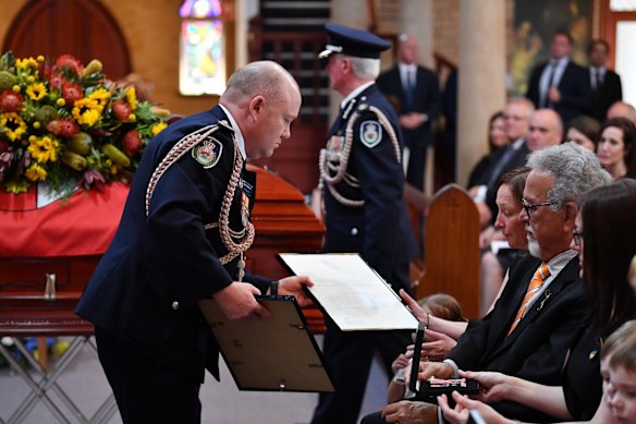 RFS Commissioner Shane Fitzsimmons presents Rural Fire Service volunteer Andrew O'Dwyer's wife Melissa with commendations.