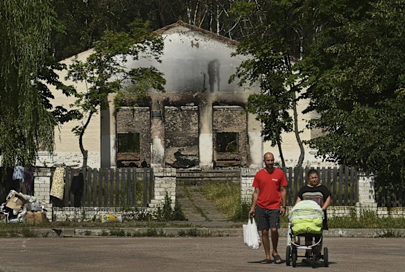 Residents walk past the remains of a destroyed building in the village of Yahidne.  