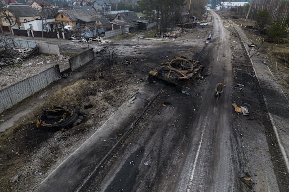 Oleksandr, 81, rides a bicycle near a destroyed Russian tank in the outskirts of Kyiv. Russian forces shelled Kyiv suburbs, two days after the Kremlin announced it would significantly scale back operations near both the capital and the northern city of Chernihiv to increase trust between the two sides.