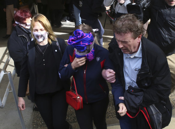 The 19-year old British woman covers her face as she leaves from the court.