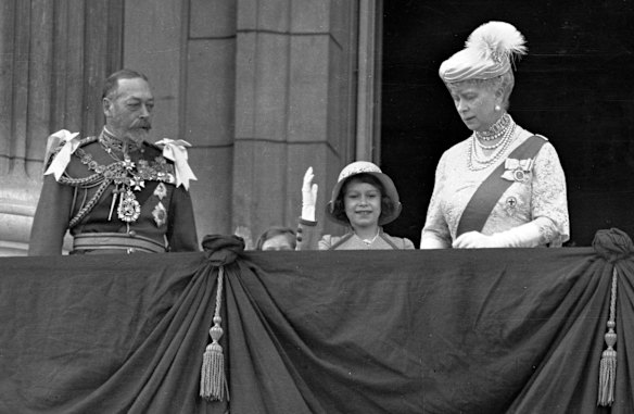 Princess Elizabeth waves as she stands on the balcony of Buckingham Palace, with her grandparents King George V and Queen Mary on May 6, 1935.