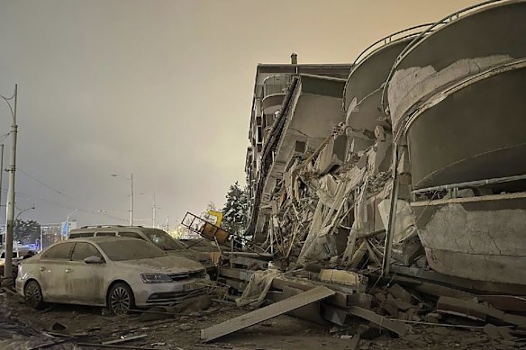 Damaged vehicles sit parked in front of a collapsed building after an earthquake in Diyarbakir.
