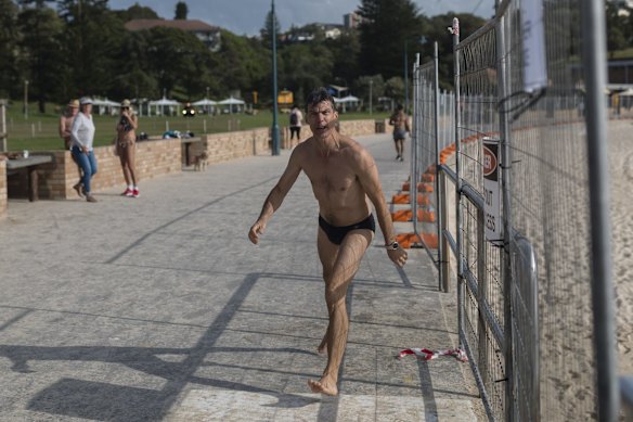 A man is seen jumping over the barricade at Bronte beach. 