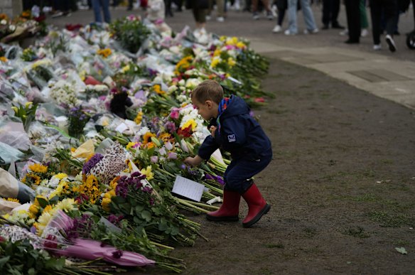 A young boy lays down a flower outside the gates of Windsor Castle in Windsor, England.
