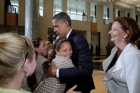 President of the United States Barack Obama is hugged by Chelsea Gallagher of Dungog Primary School as Prime Minister of Australia Julia Gillard looks on in the Marble Foyer at Parliament House Canberra.