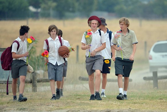 Friends arrive at the Tyabb oval to place flowers.