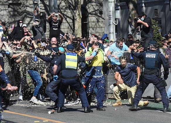 Protesters are doused in capsicum spray after breaking police lines outside state parliament on Spring Street.