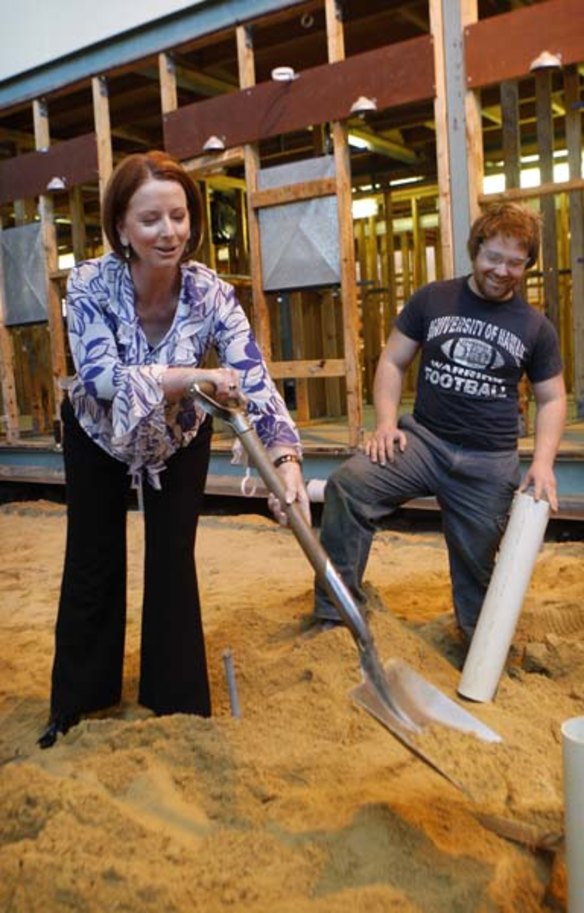 Gillard shovels sand while a second year apprentice plumber looks on in May 2010.