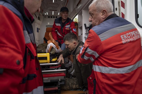 Ambulance workers help an injured Ukrainian serviceman to move to a hospital in Donetsk region.
