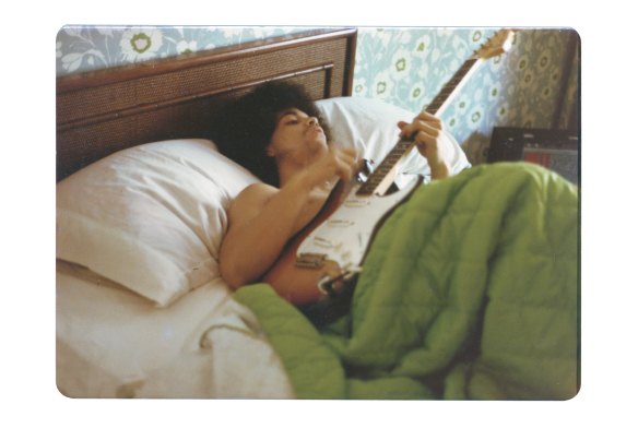 Prince plays a guitar in bed at his new home on France Avenue, April 1978. 