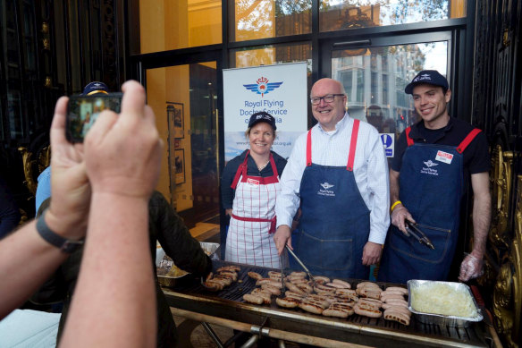 Australia’s High Commissioner to the UK George Brandis serves democracy sausages to voters at Australia House in London. 