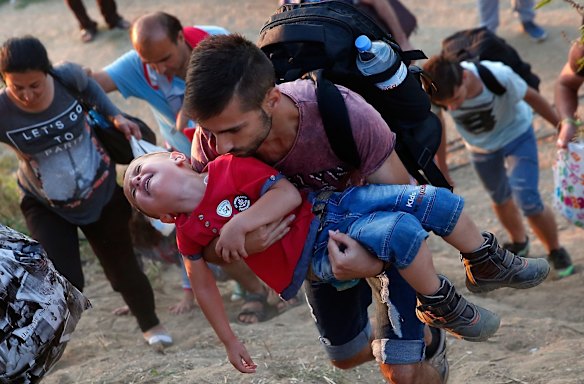 A young Syrian boy cries as his father carries him up a steep hill as they walk to a border crossing on the Greek and Macedonian border.