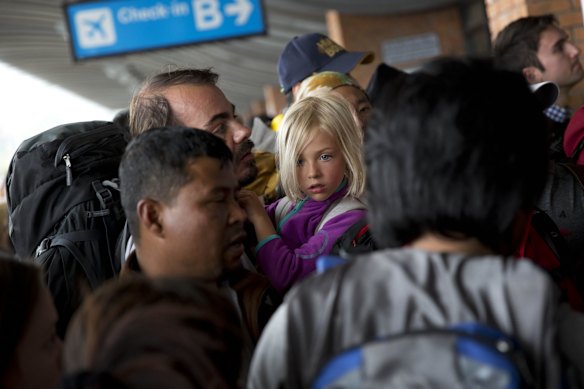 A German national girl and a man wait in a queue to go inside the Kathmandu international airport, in Kathmandu, Nepal, Sunday, April 26, 2015.