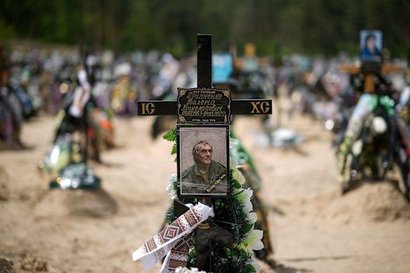 The photograph of a victim of the battles for Irpin and Bucha adorns a cross among other floral tributes, crosses and photographs of people lost in those battles at Irpin cemetery on May 16, 2022.