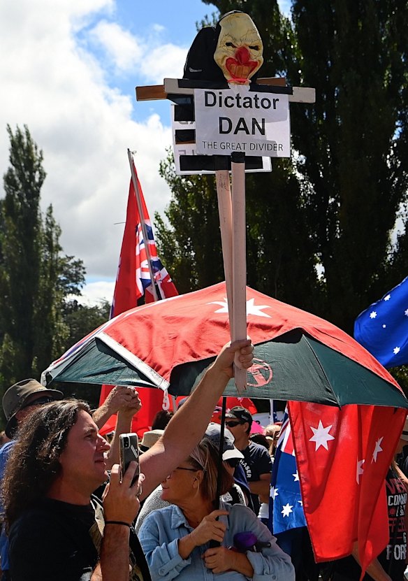 A protester with the Convoy to Canberra rally holds an anti-Dan Andrews placard outside Old Parliament House.