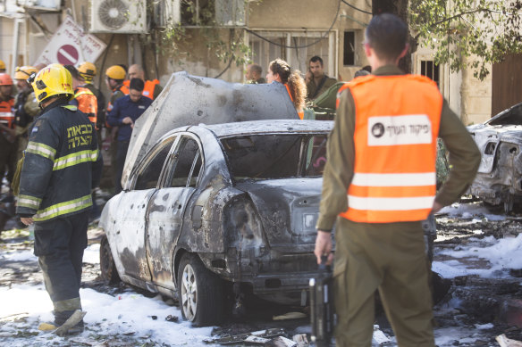 Security force personnel look at a burned car after a rocket fired from Gaza Strip hit on Saturday. 