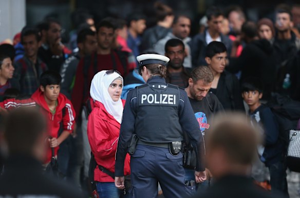 A young Muslim woman speaks to a policewoman as migrants who had arrived on a train from Hungary transfer to a chartered commuter train at Munich Hauptbahnhof main railway station in Munich, Germany.