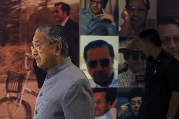 Malaysian Prime Minister Mahathir Mohamad walks by a board displaying his photos in Putrajaya, Malaysia.