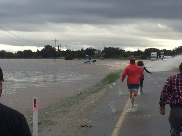 Rescuers rush to a car that is stranded in flood waters in Maitland.