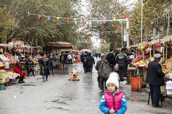 Anti-riot police patrol a market as people shop at food stalls in the Old City in Kashgar, Xinjiang autonomous region, China.