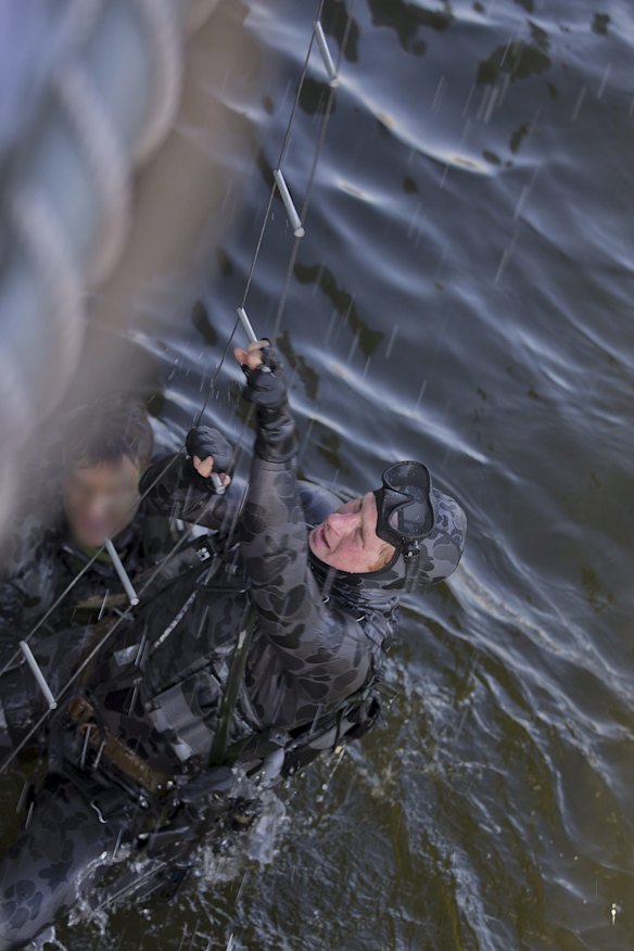 Captain Wales climbs a ladder during a water insertion with Royal Australian Navy Clearance Divers.