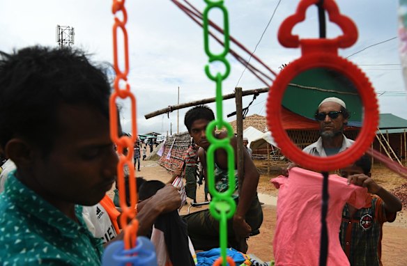 Men sort through clothes on a cart available to buy on a road.