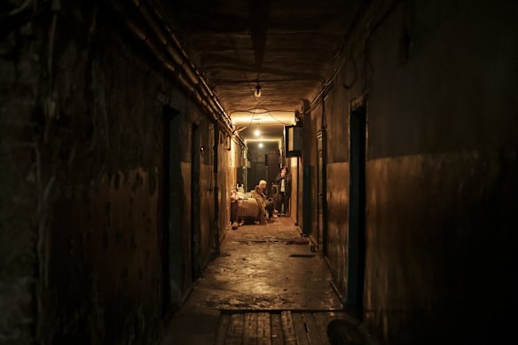 A family sits in the hallway of their apartment building as Russian attacks continue in Kharkiv.