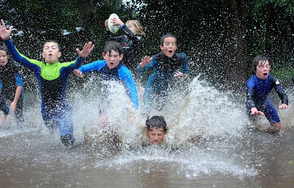 Kids playing footy in water logged Glastonbury Gardens at Austinmer. 
