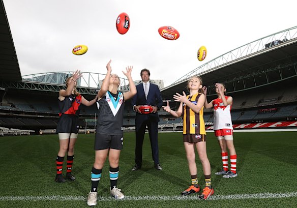 AFL CEO, Gillon Mclachlan poses with young footballers Nora Don, Fadilla Taleb, Leni Burgoyne and Layla Rabah during an AFLW media opportunity at Marvel Stadium in 2021.