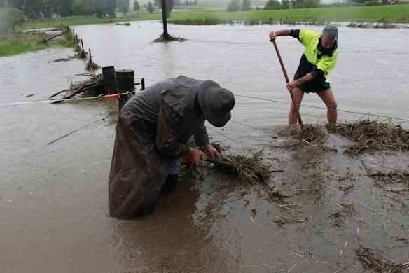 Residents clear debris from fences along the Cooma Creek.