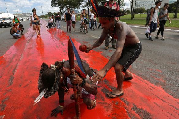 Brazilian indigenous people paint a road to depict the blood of those killed in the struggle for their lands.