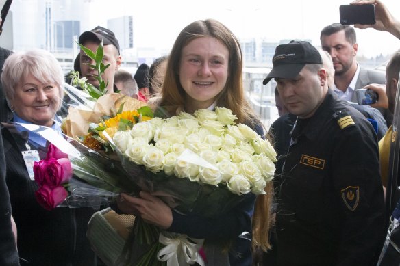 Maria Butina holds a bunch of flowers as she lands in Russia.