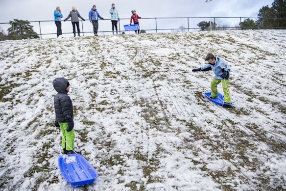 Children play in the snow at Blackheath Oval.