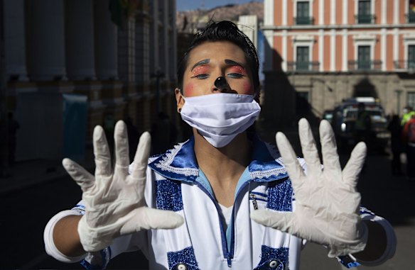 A street performer wearing protective gear strikes a pose at the popular Murillo square empty of visitors since the government has restricted residents to essential shopping in the mornings in an attempt to contain the spread of the new coronavirus, in La Paz, Bolivia.