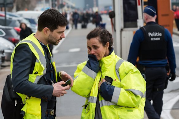 People react outside Brussels airport after explosions rocked the facility in Brussels, Belgium.